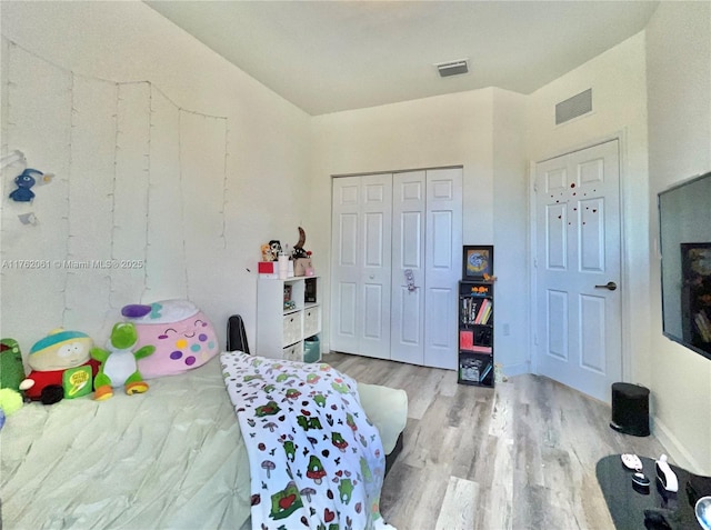 bedroom with a closet, visible vents, baseboards, and wood finished floors