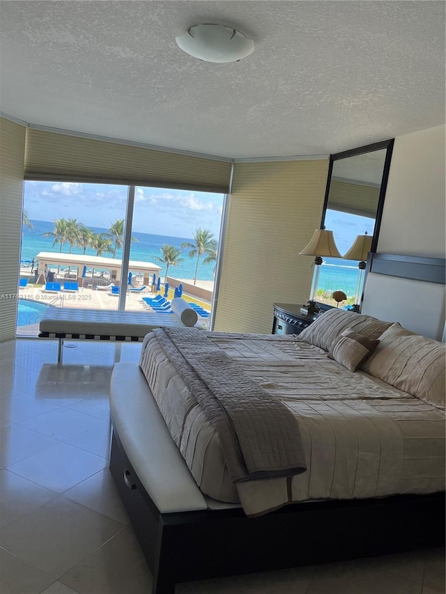 bedroom featuring tile patterned floors, a textured ceiling, and a water view