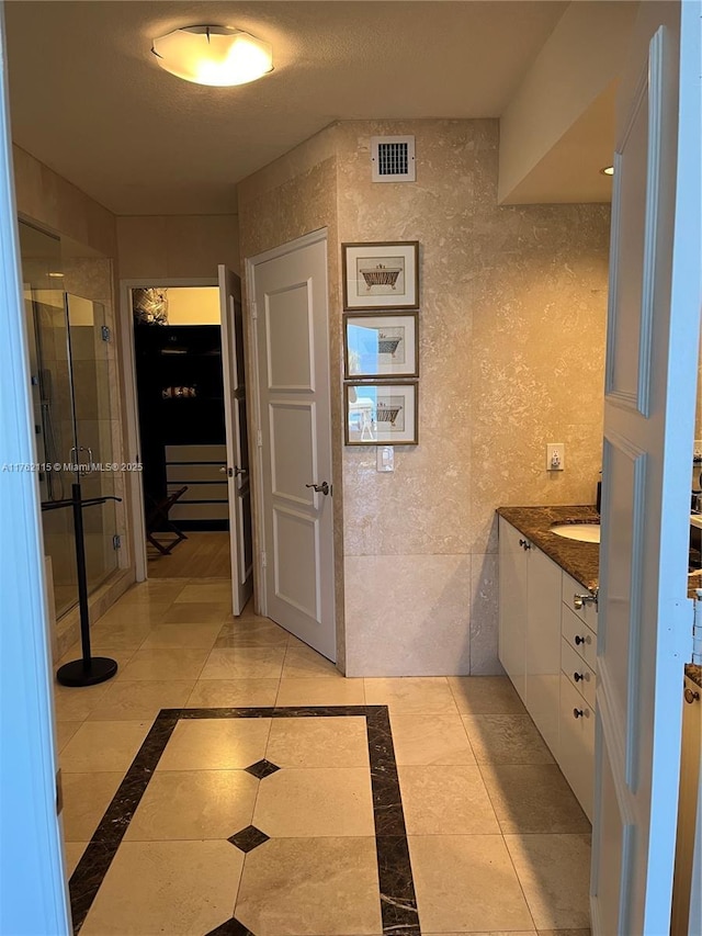 bathroom featuring vanity, a shower stall, and visible vents