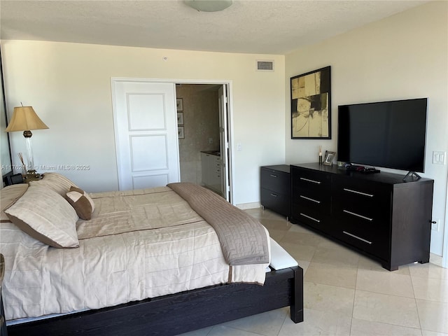 bedroom featuring light tile patterned flooring, visible vents, and a textured ceiling