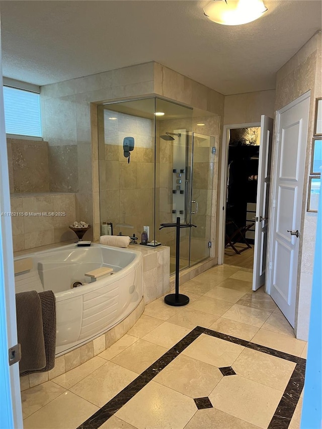 bathroom with a tub with jets, a stall shower, and a textured ceiling