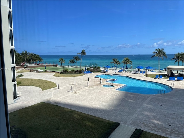 view of pool featuring a water view and a patio area