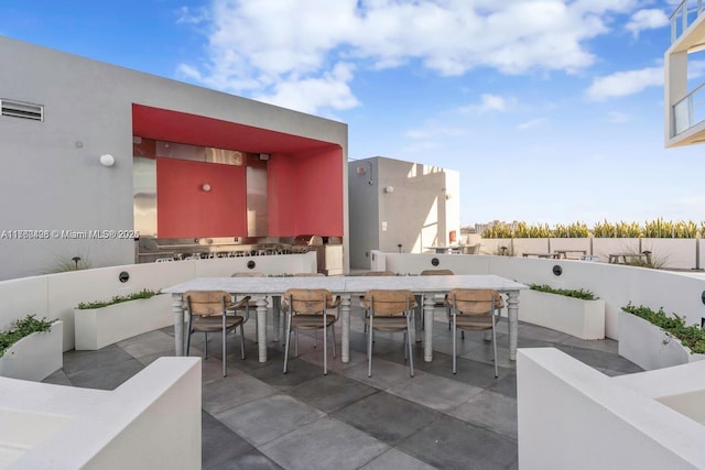 view of patio with outdoor dining space, visible vents, outdoor wet bar, exterior kitchen, and a fenced backyard