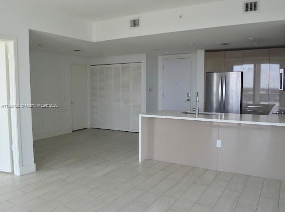 kitchen with visible vents, a sink, freestanding refrigerator, a peninsula, and light countertops