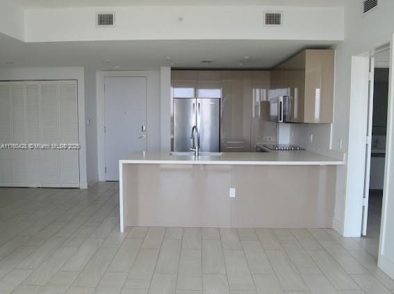 kitchen featuring a peninsula, light countertops, visible vents, and freestanding refrigerator