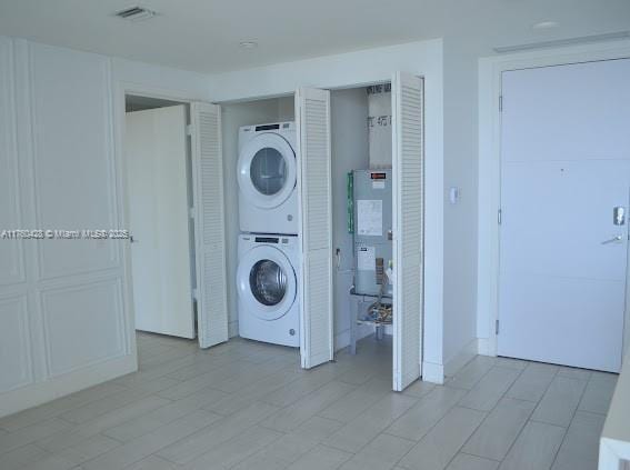 laundry room with visible vents, laundry area, and stacked washing maching and dryer