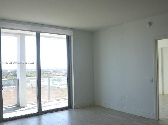 unfurnished room featuring floor to ceiling windows and baseboards