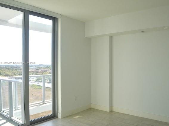 unfurnished room featuring floor to ceiling windows and baseboards