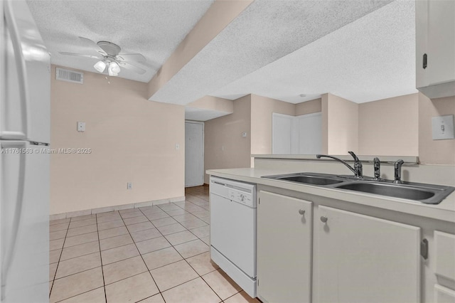 kitchen with visible vents, light tile patterned floors, freestanding refrigerator, white dishwasher, and a sink