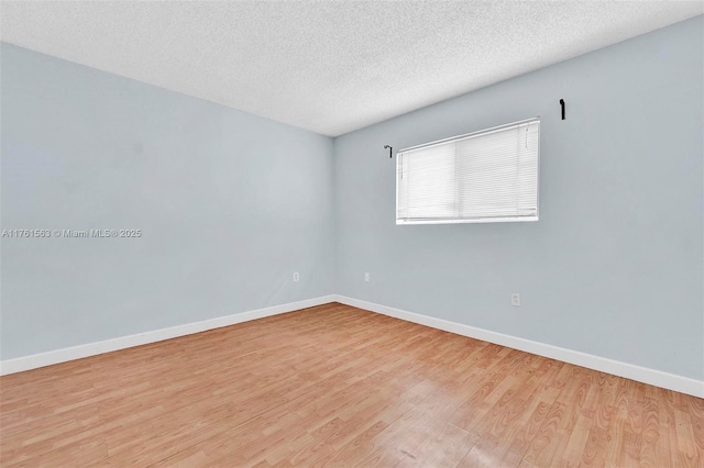 unfurnished room featuring baseboards, a textured ceiling, and wood finished floors