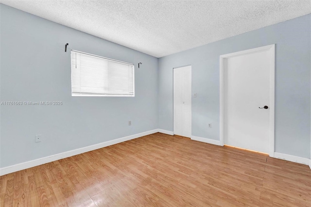 unfurnished bedroom with light wood-type flooring, baseboards, and a textured ceiling