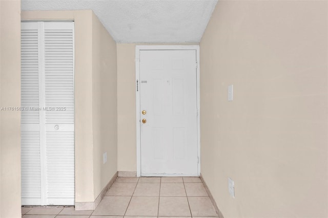 interior space with light tile patterned floors, baseboards, and a textured ceiling