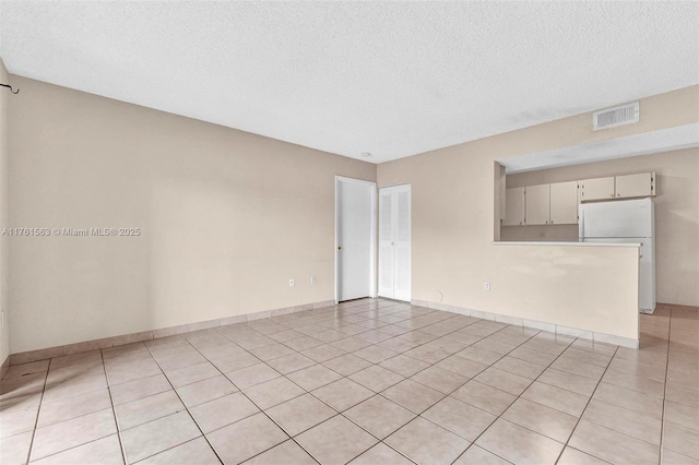 spare room with visible vents, a textured ceiling, and baseboards