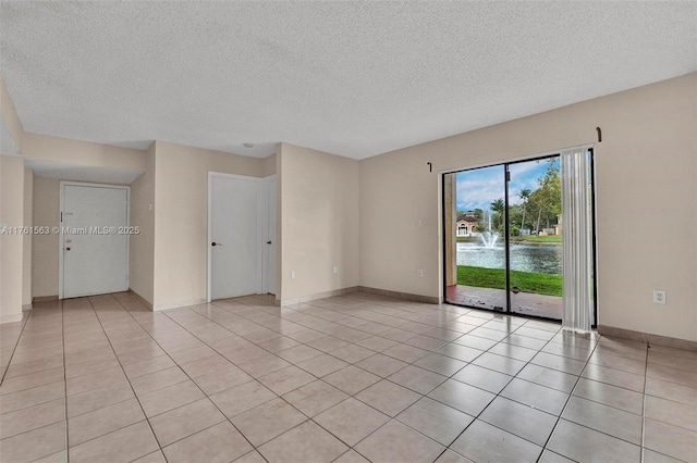 empty room featuring light tile patterned floors, baseboards, and a textured ceiling