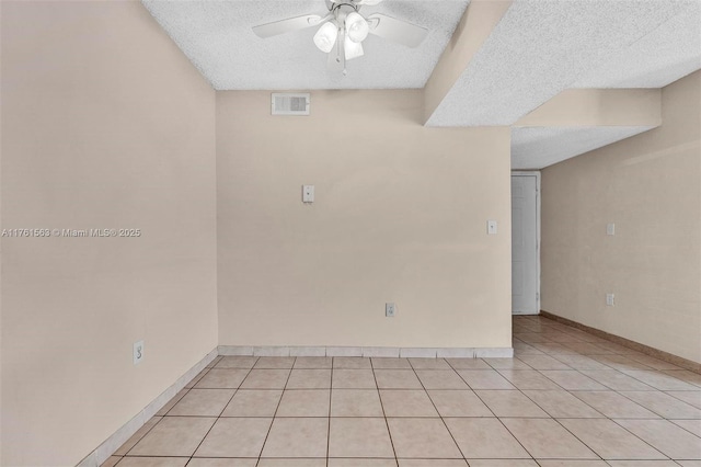 spare room featuring visible vents, a textured ceiling, light tile patterned flooring, baseboards, and ceiling fan