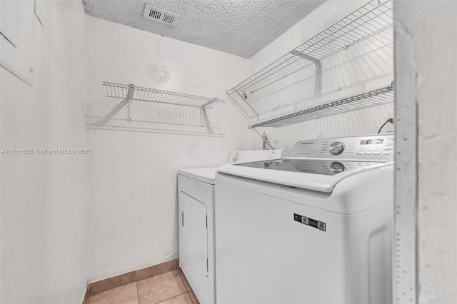 laundry room with light tile patterned floors, visible vents, laundry area, a textured ceiling, and independent washer and dryer