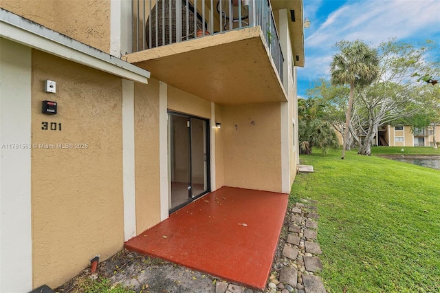 doorway to property featuring a lawn and stucco siding