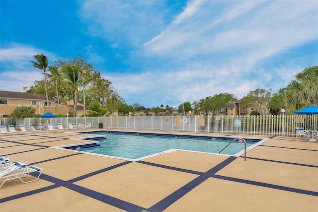 community pool with a patio area and fence