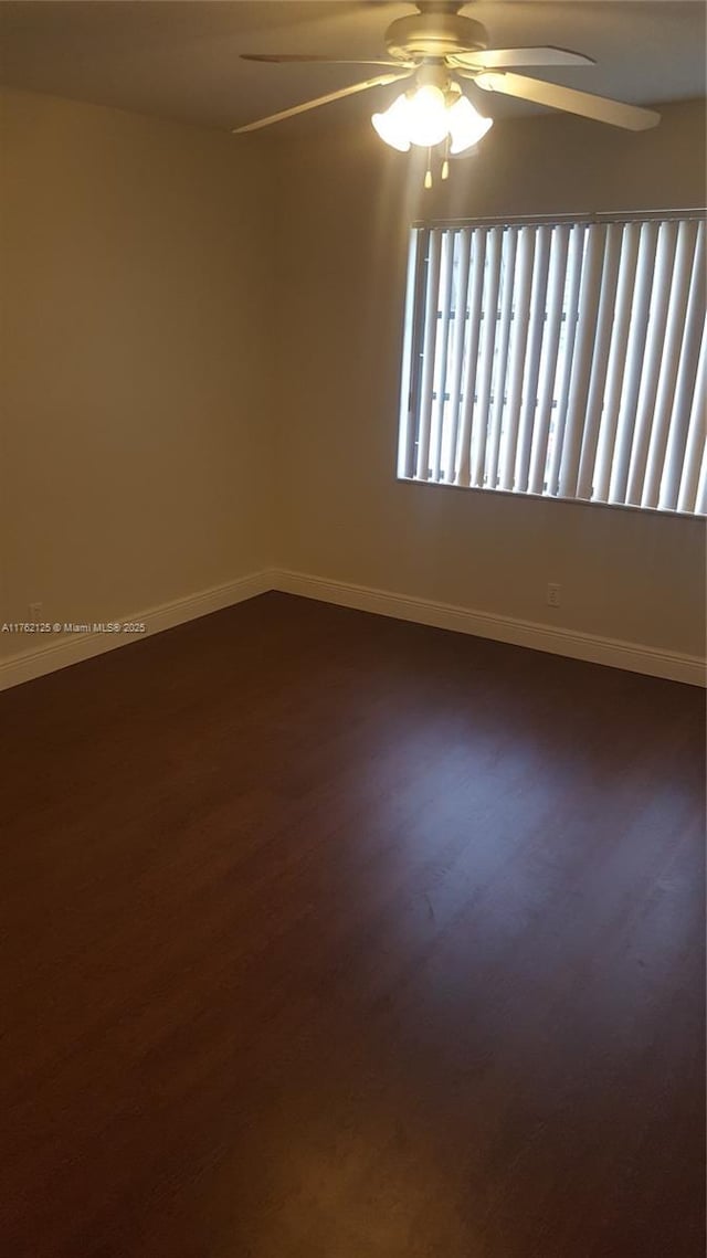 unfurnished room featuring a ceiling fan, dark wood-style floors, and baseboards