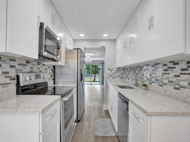 kitchen with a sink, stainless steel appliances, white cabinets, and light wood finished floors