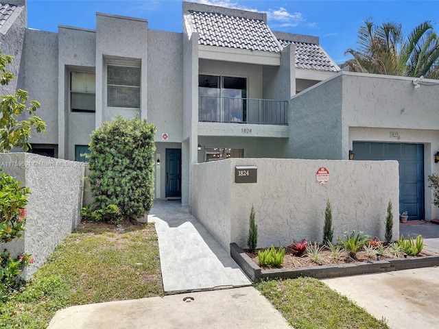 multi unit property with a fenced front yard, stucco siding, a tile roof, and a balcony