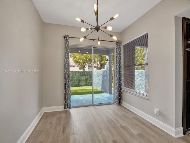 unfurnished dining area with a chandelier, baseboards, and wood finished floors