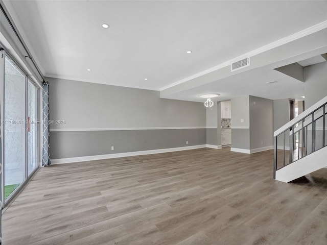 unfurnished living room featuring visible vents, baseboards, stairs, and light wood finished floors