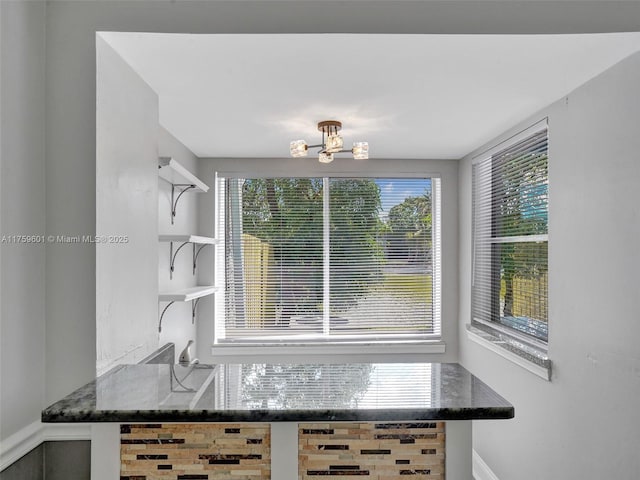 interior space featuring open shelves, a notable chandelier, and dark stone countertops