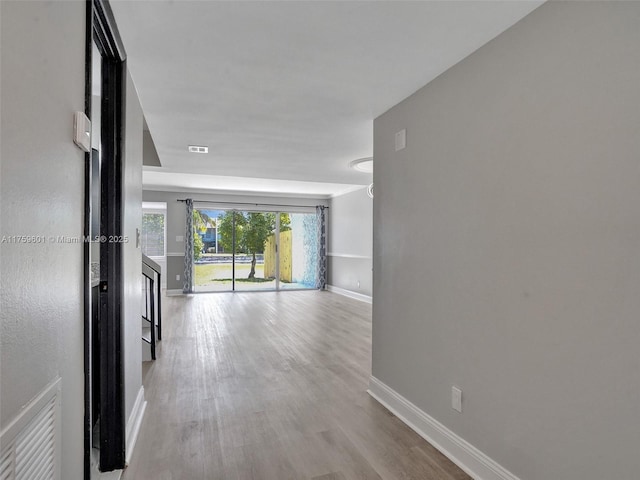 corridor with visible vents, wood finished floors, and baseboards