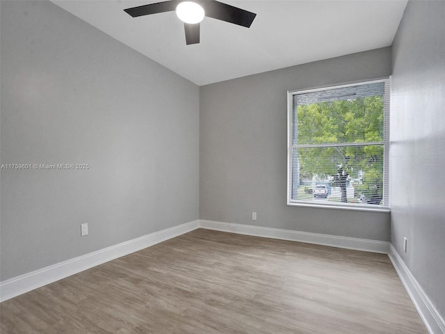 empty room featuring wood finished floors, baseboards, and ceiling fan