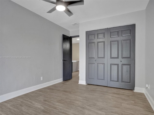 unfurnished bedroom featuring light wood-type flooring, baseboards, a closet, and ceiling fan