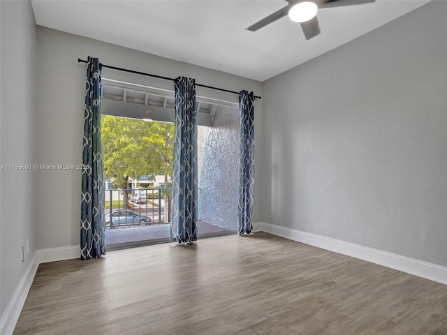 empty room featuring baseboards, wood finished floors, and a ceiling fan