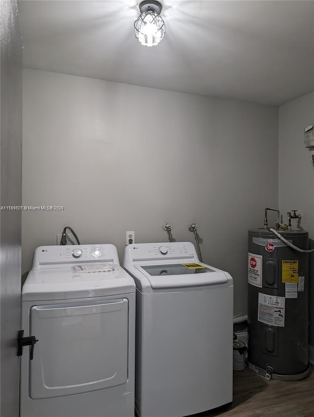 clothes washing area with electric water heater, wood finished floors, laundry area, and washer and clothes dryer