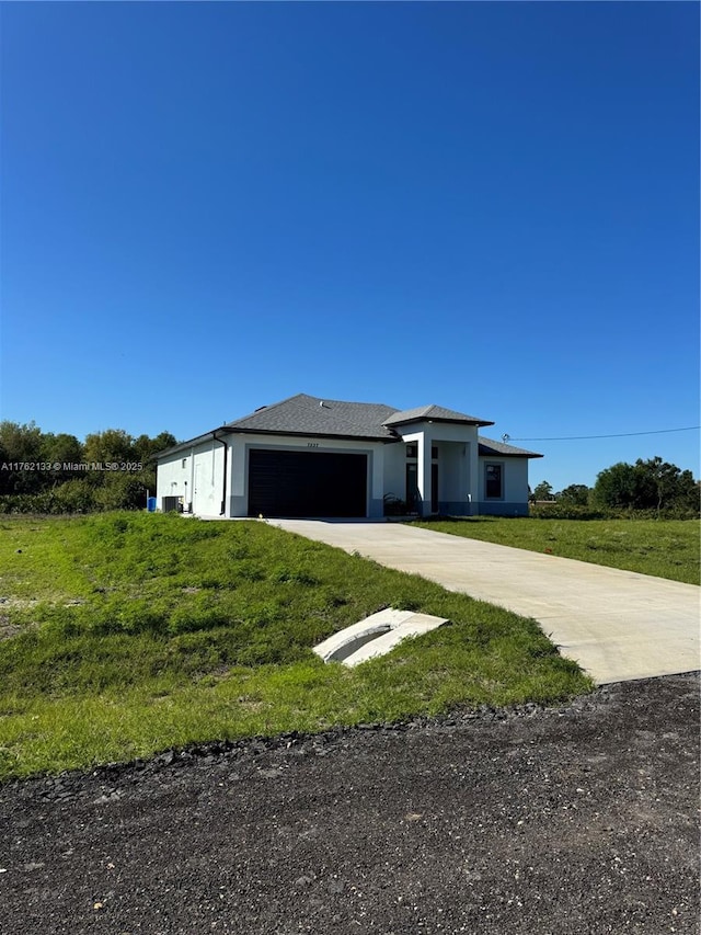 view of front of house with a garage, concrete driveway, a front yard, and stucco siding