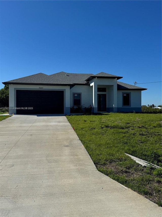 view of front of home featuring a shingled roof, a front yard, stucco siding, a garage, and driveway