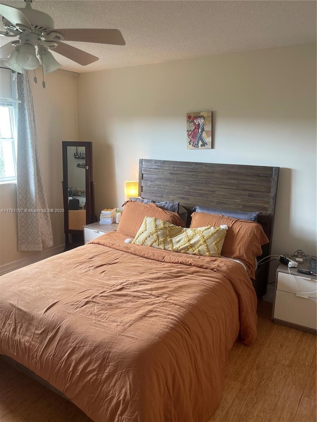 bedroom featuring a textured ceiling, wood finished floors, and a ceiling fan