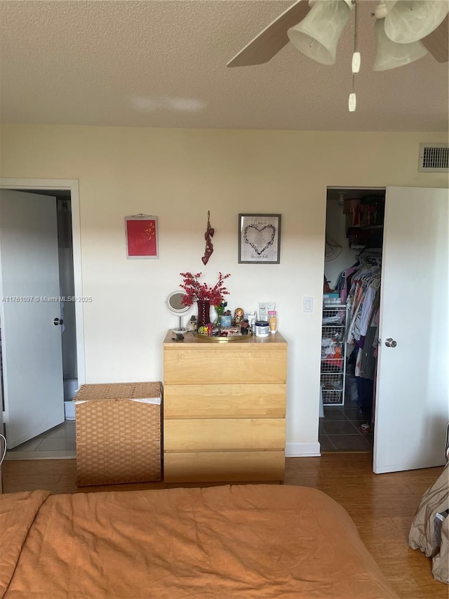 bedroom featuring wood finished floors, visible vents, a spacious closet, a closet, and a textured ceiling