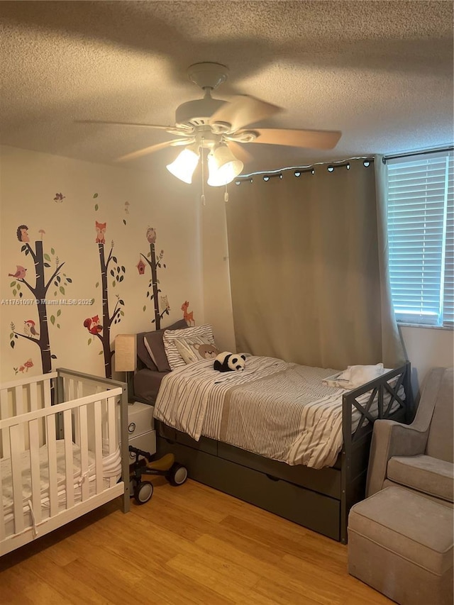 bedroom with light wood-style floors, a ceiling fan, and a textured ceiling