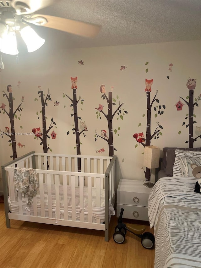 unfurnished bedroom with light wood-style flooring, a nursery area, and a textured ceiling