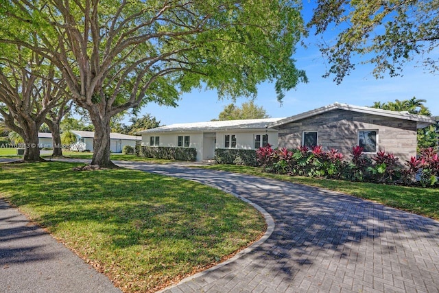 single story home featuring decorative driveway and a front yard