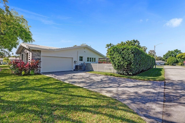 view of front of house featuring cooling unit, an attached garage, driveway, and a front yard