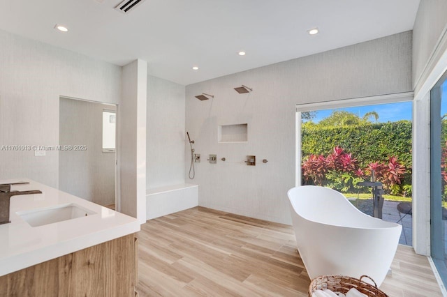 full bath with a sink, visible vents, a freestanding bath, and wood finished floors