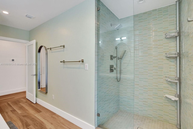 full bath featuring visible vents, wood finished floors, baseboards, and walk in shower