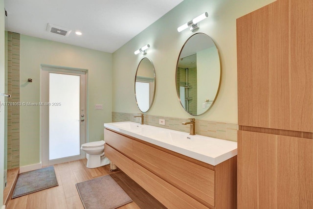 full bath featuring a sink, visible vents, toilet, and double vanity