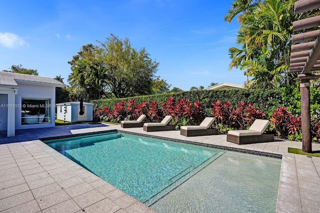 view of pool with an outdoor structure, a patio area, and a fenced in pool