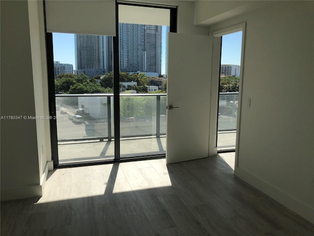 empty room with a view of city, baseboards, and wood finished floors