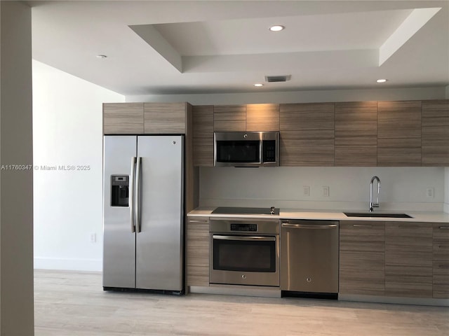 kitchen with visible vents, a sink, light countertops, appliances with stainless steel finishes, and a raised ceiling