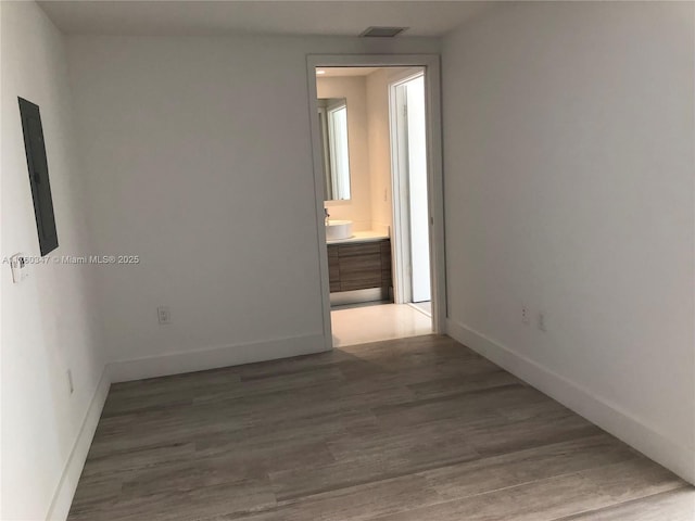 unfurnished room featuring visible vents, electric panel, wood finished floors, and baseboards