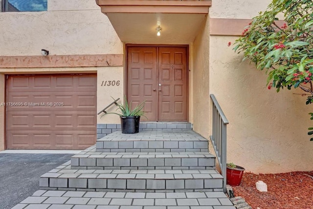 doorway to property with stucco siding and an attached garage