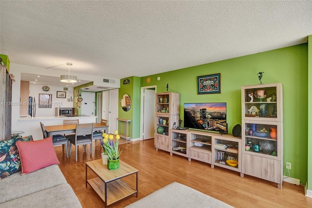 living room with visible vents, a textured ceiling, and wood finished floors